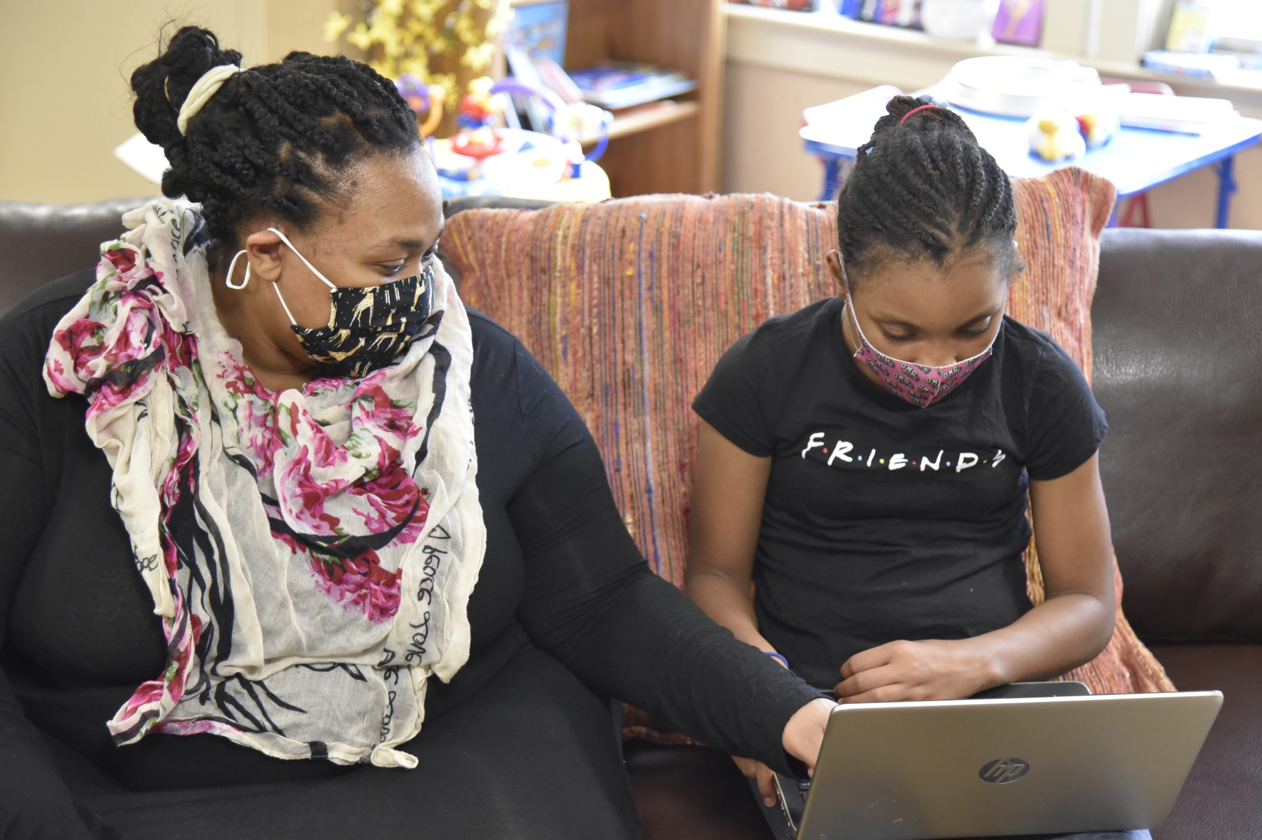 Young girl sitting next to mom with a laptop on her lap