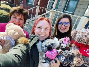 Three smiling woman holding stuffed animals