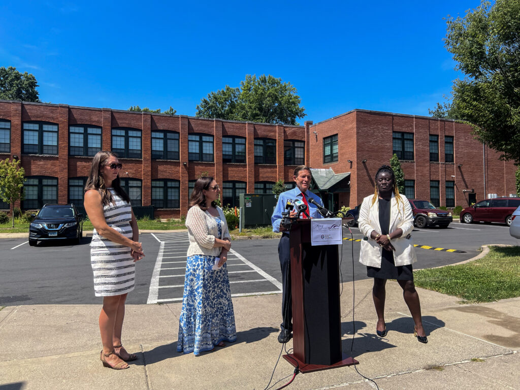 A photo of Senator Richard Blumenthal with CEO Kara Capone, Amy Pelletier from the Partnership for Strong Communities and Jennifer Quaye-Hudson from the Open Communities Alliance outside the Beaumont Lofts.