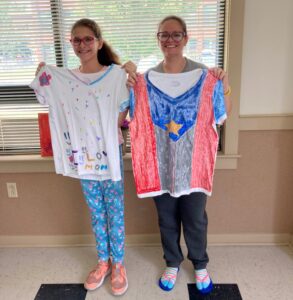 A mother and daughter holding up hand-painted t-shirts